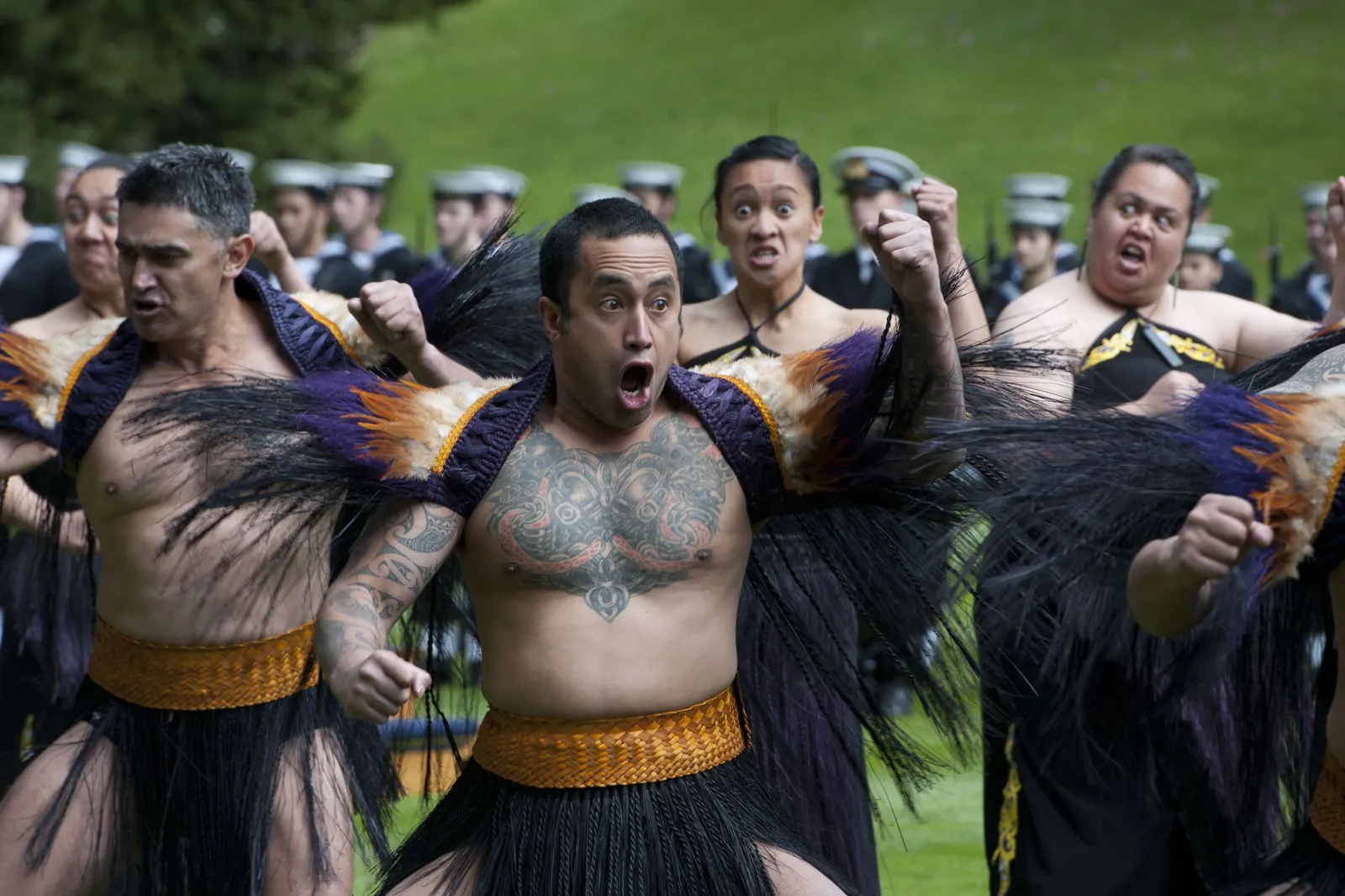 Performers in feathered cloaks give a haka of welcome with their eyes wide in pūkana; this was not at Whakarewarewa
